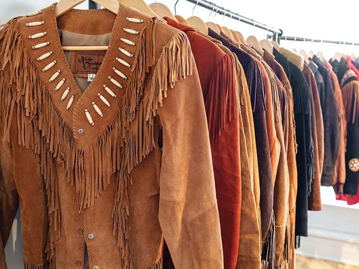 A rail of vintage suede fringe jackets, the nearest with a beaded yoke