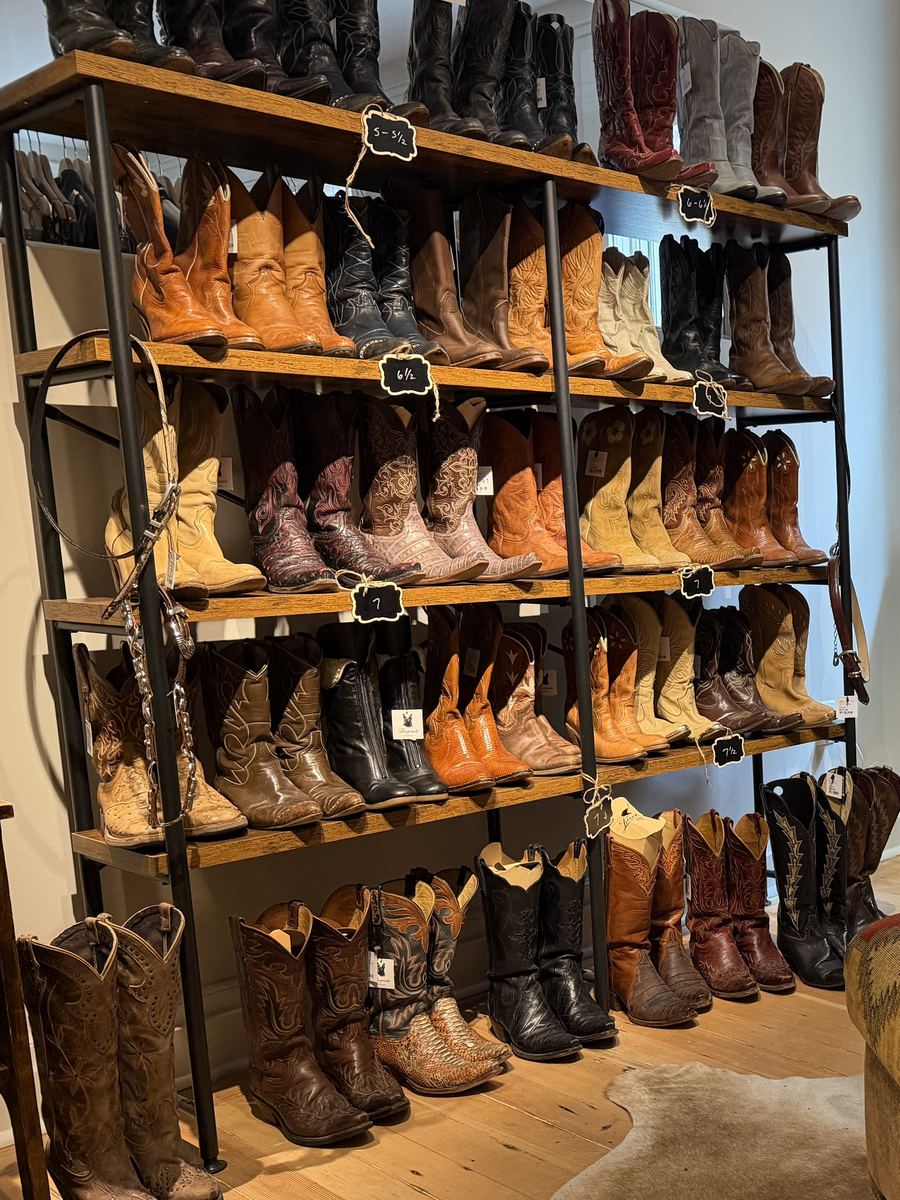 Shelves of vintage cowboy boots sorted by size on chalkboard tags